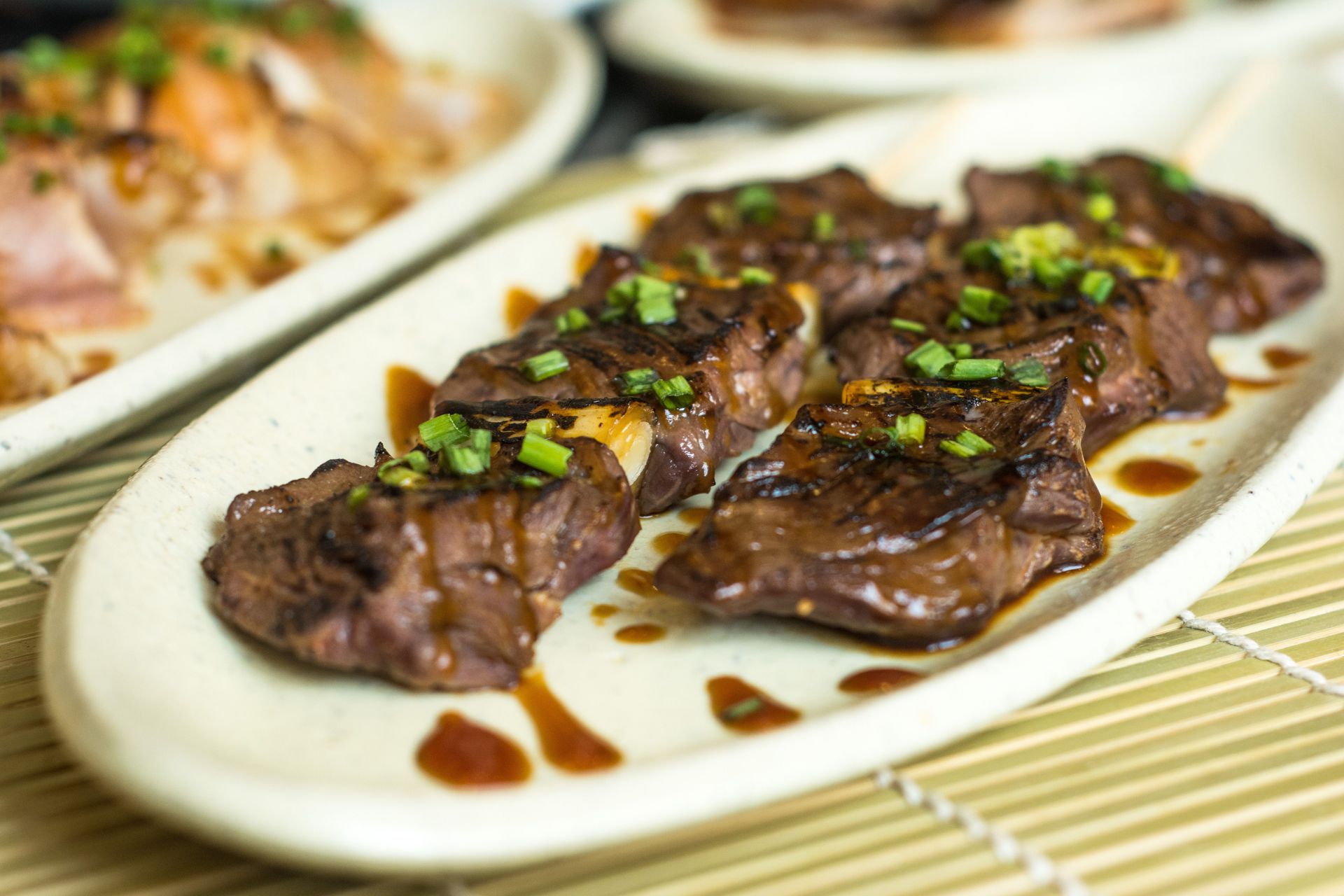 Close-up of delicious grilled beef skewers garnished with green onions on a plate.